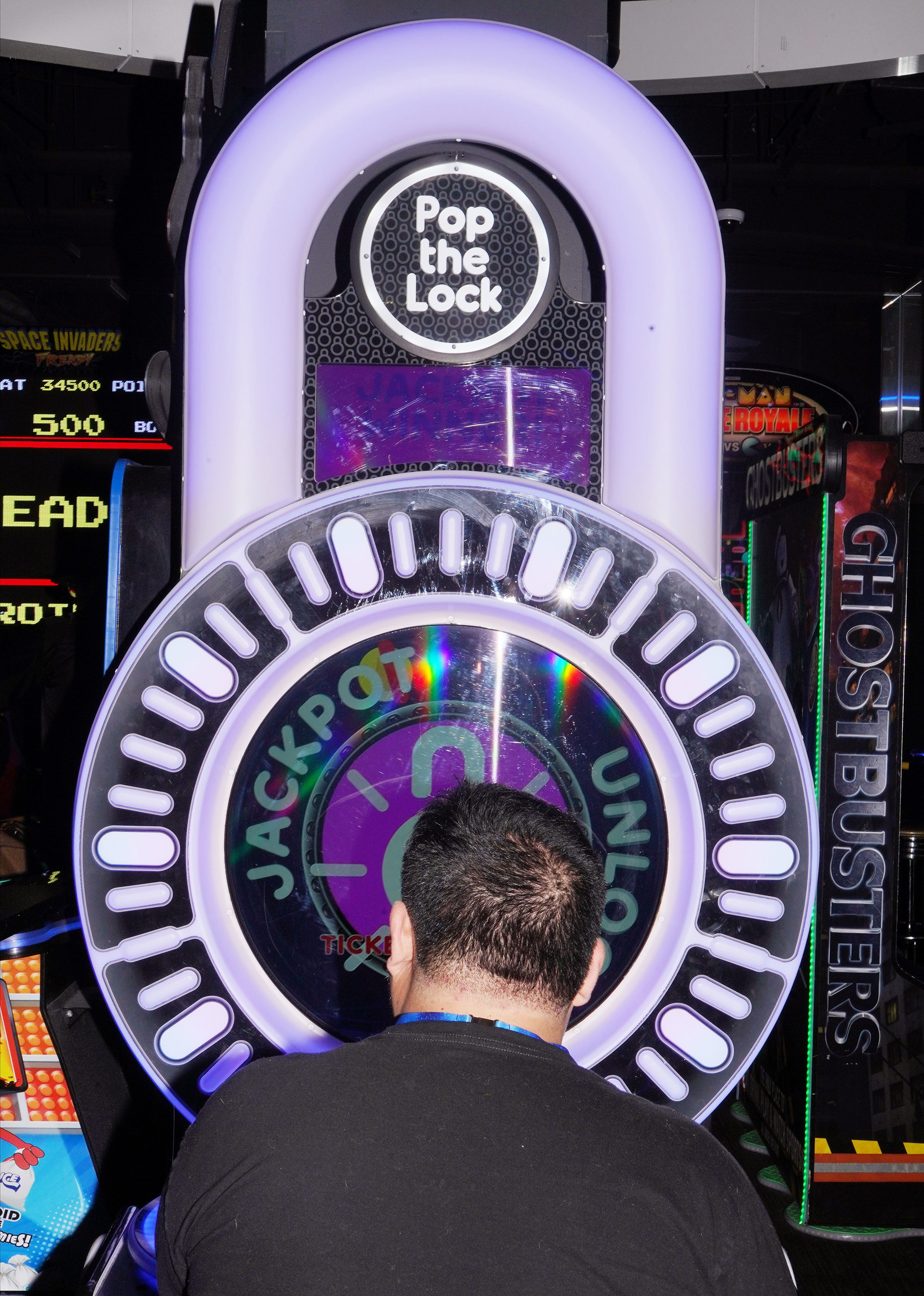 The back of a man's head as he plays an arcade game called 'Pop the Lock'