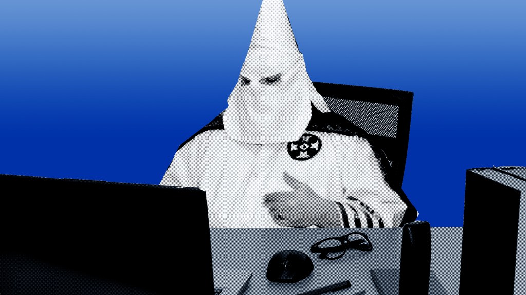 Ein Mann mit Ku-Klux-Klan-Haube sitzt vor einem PC