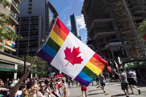 A man holds a flag on a hockey stick during the Pride parade in Toronto on June 25, 2017.