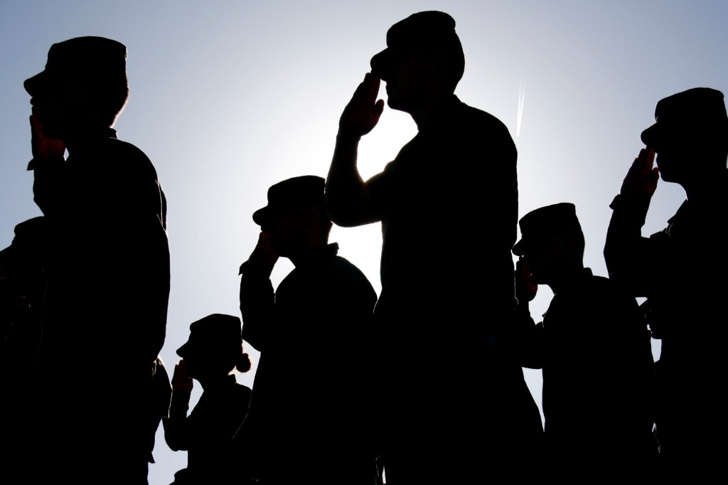 Photo of military service members saluting.