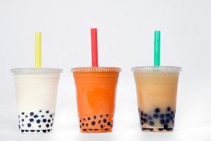 three cups of bubble tea in front of a white background: one white, one red, and one tan