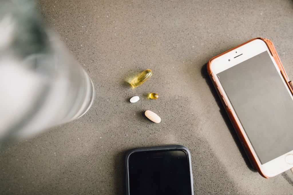 vitamins on table with phones and glass of water