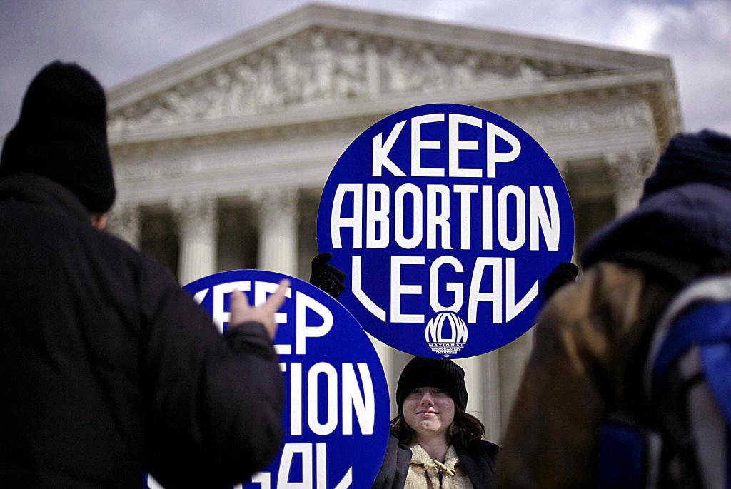 A protester outside the Supreme Court holds a blue sign reading "Keep Abortion Legal"