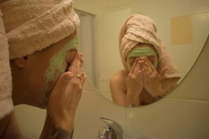 Woman washing face in front of mirror.