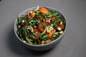 a gray bowl of raw collard green salad with fennel, fried plantains, and peaches marinated in molasses, sherry vinegar, and sumac