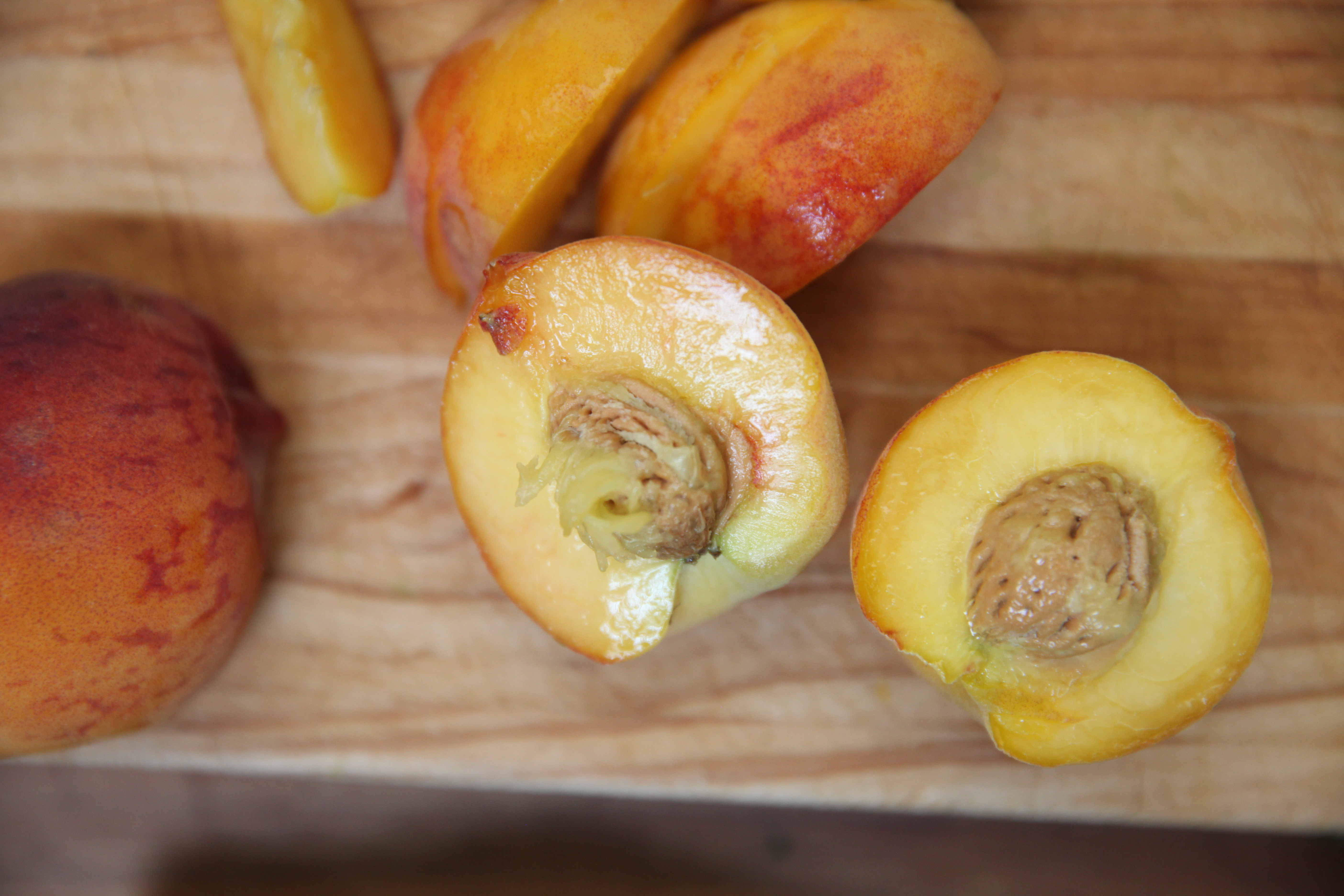 halves of a peach on a wooden cutting board