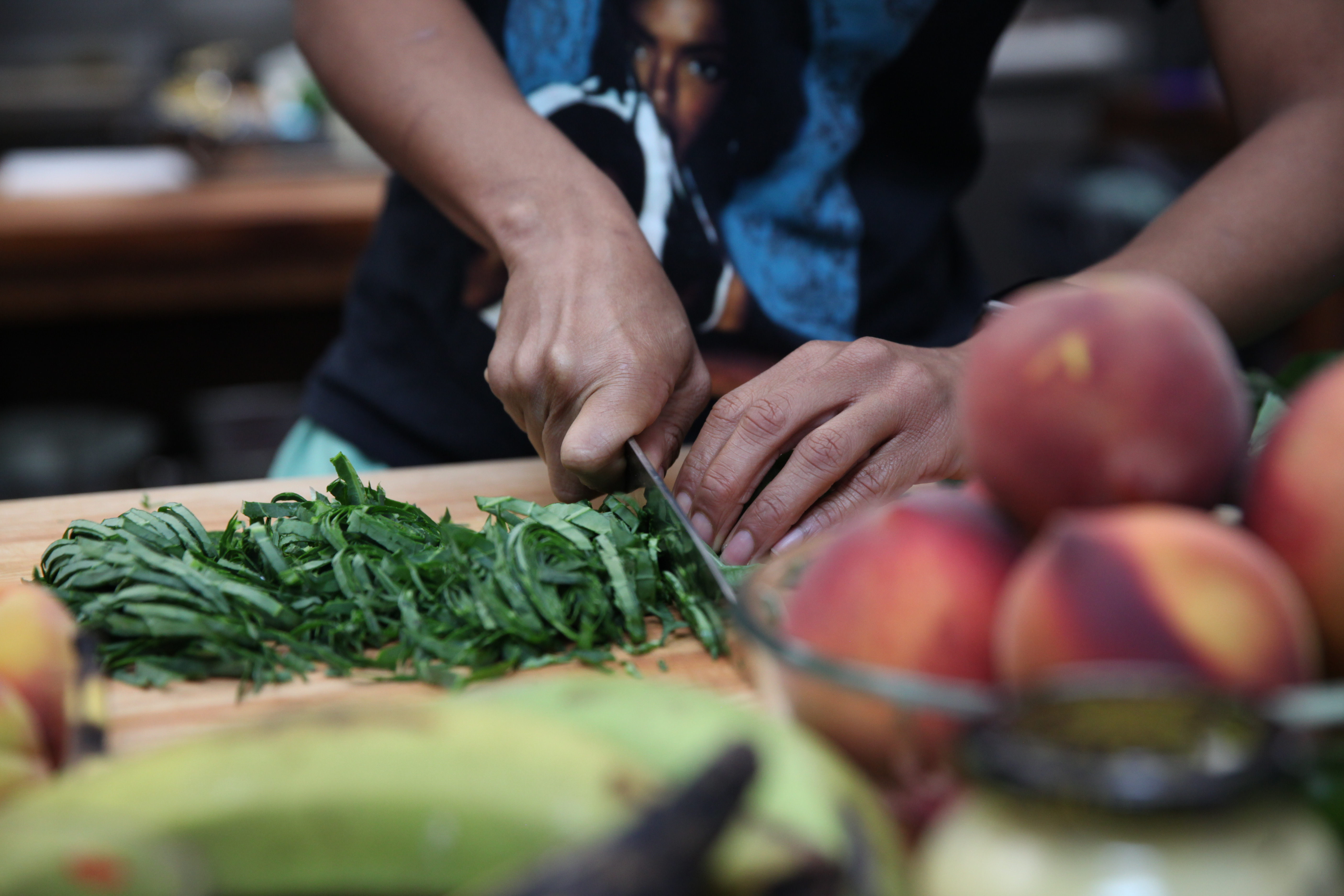 chef ashleigh shanti cutting collard greens on a wooden cutting board