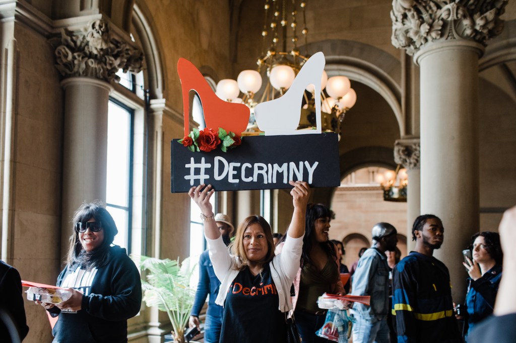 A member of Decrim NY holds up a sign in support of decriminalizing sex work in Albany