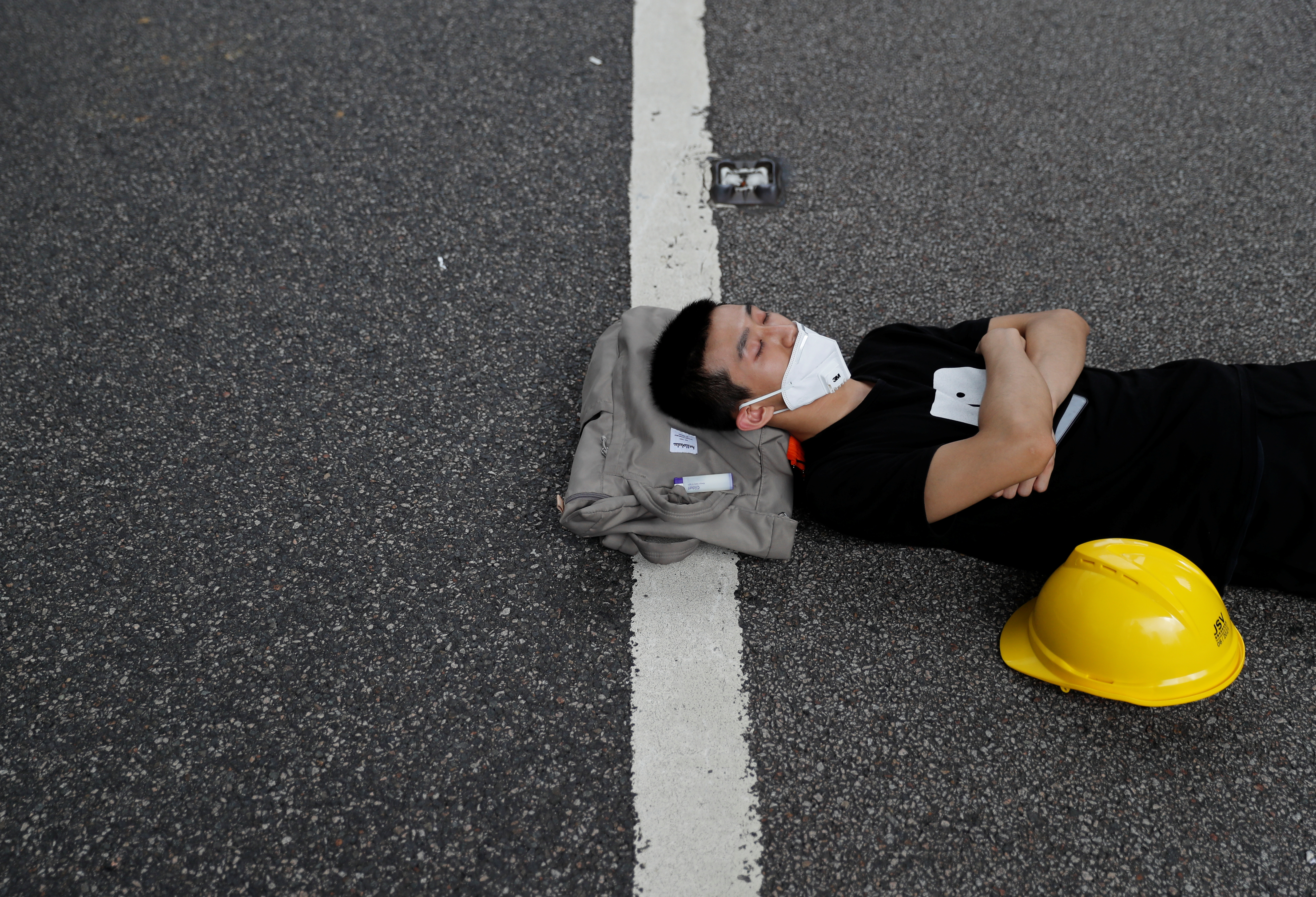 A protester, who camped out overnight, sleeps along a road near the Legislative Council building, amidst demonstrations against the extradition bill.