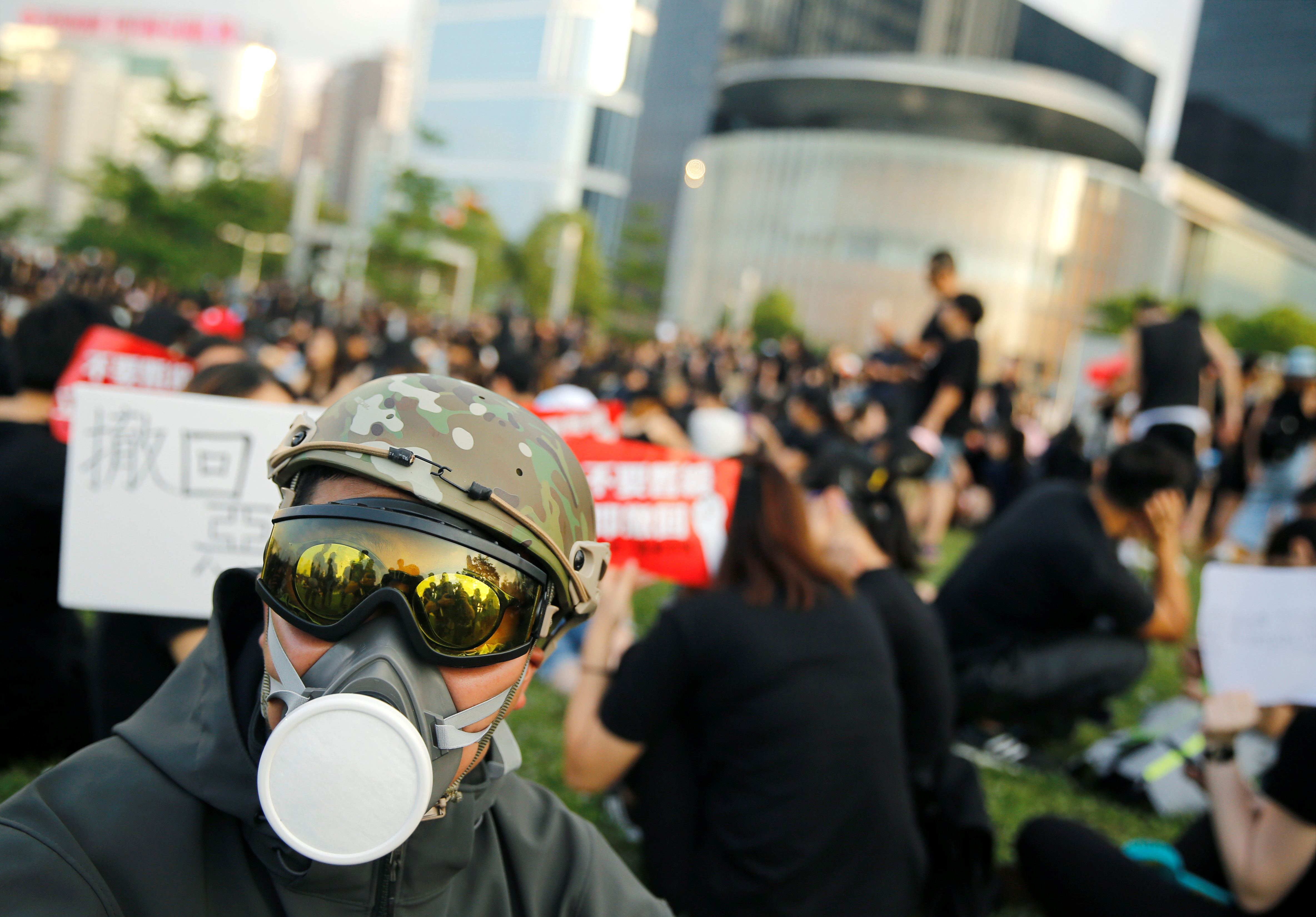 A protester wearing a helmet and mask sits in front of the Legislative Council building during demonstrations.