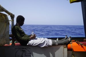 Ein Migrant schaut vom Deck der Sea Watch 3 übers Meer