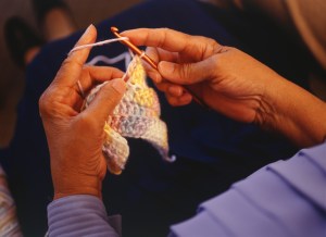 Close up of a black woman's hands, while knitting