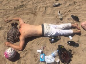 Sunburned man lying asleep on beach during summer heatwave