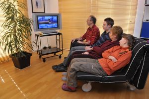 Familie sitzt vor Fernseher und schaut Nachrichten