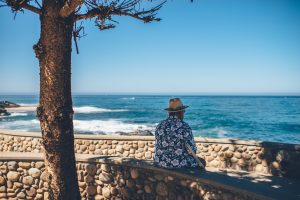 homem sentado num banco a olhar para o mar