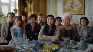 The Farewell cast, sitting on one side of a kitchen table, facing the camera