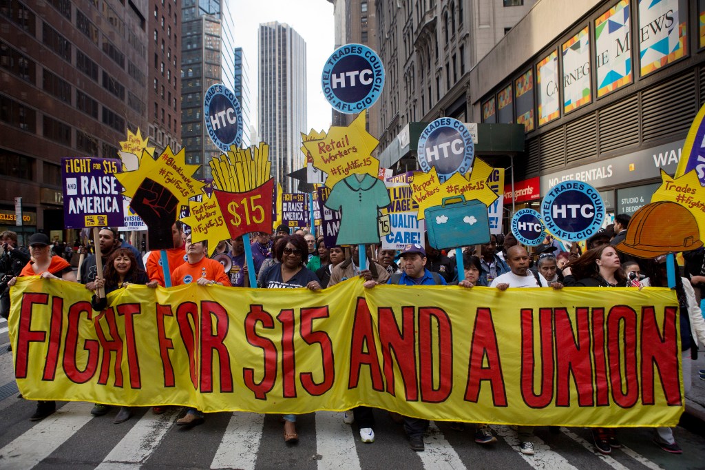 Protesters hold up a banner reading, "Fight for $15 and a union."