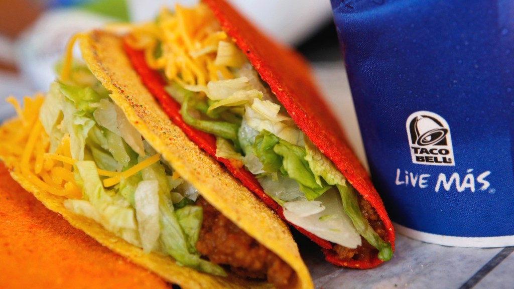 two doritos locos tacos from taco bell, next to a blue soda cup that says "live más"