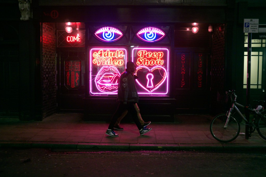 ​A peep show sign fronting a restaurant in Soho, London.