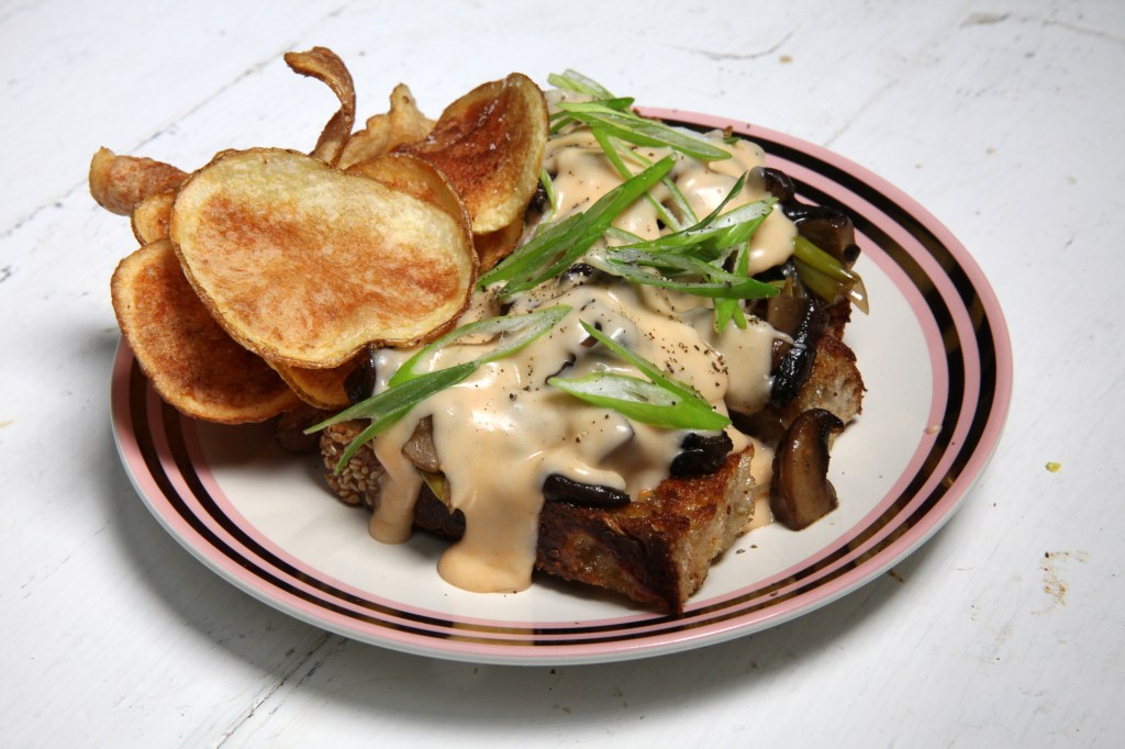 potato chips and the mushroom and cheese melt from gertie in williamsburg, brooklyn, on top of a white, pink, and gold plate in the munchies test kitchen