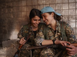 Die kurdischen Soldatinnen Silava und Berivan sitzen lachend in einer verlassenen IS-Basis in Sindschar und werden von Joey Lawrence fotografiert