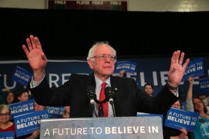 Bernie Sanders with his hands up at a rally