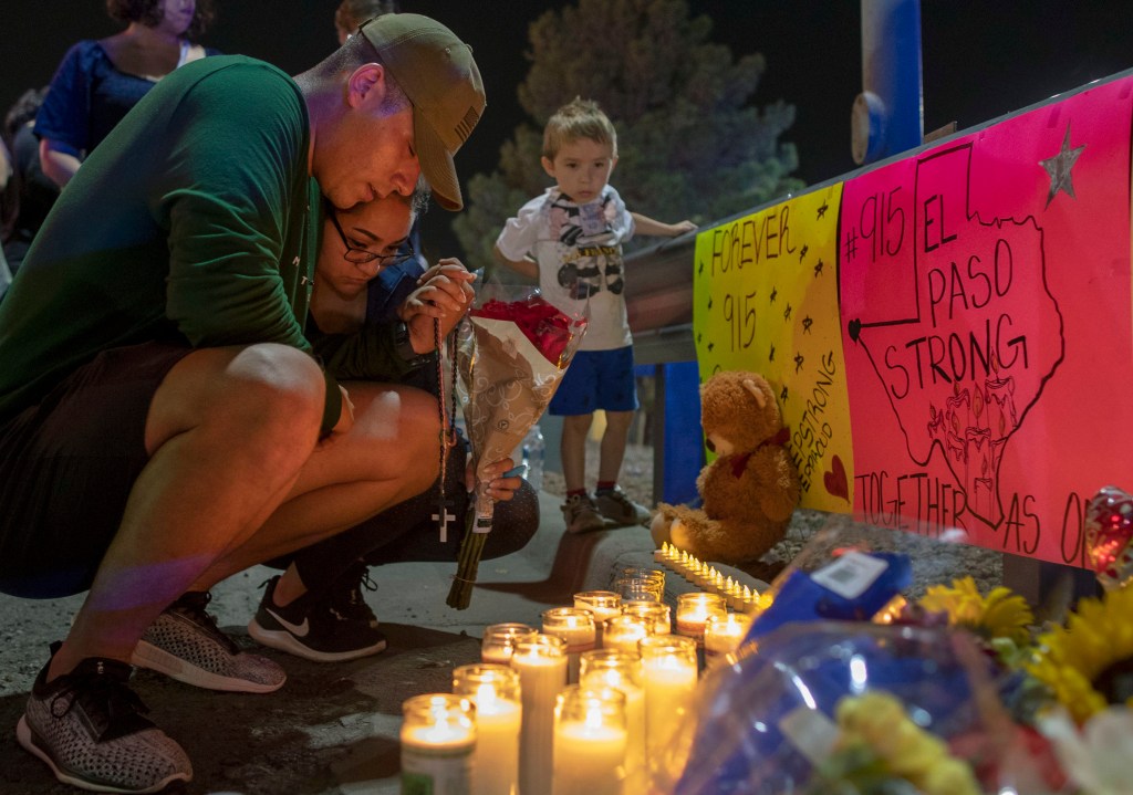 Rene Aguilar and Jackie Flores pray at a makeshift memorial for the victims of Saturday's mass shooting at a shopping complex in El Paso, Texas, Sunday, Aug. 4, 2019.