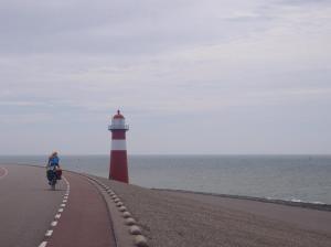 Een vrouw fietst langs een vuurtoren