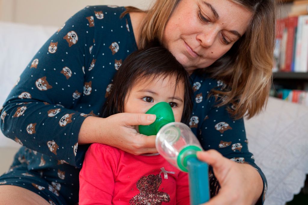 Woman giving nebulizer treatment to a toddler