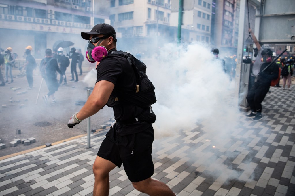 Ein Demonstrant wirft ein Tränengas-Geschoss zurück auf die Polizei