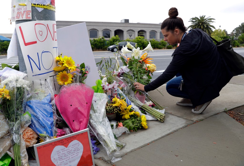 A woman leaves flowers on a growing memorial across the street from the Chabad of Poway synagogue in Poway, Calif., on Monday, April 29, 2019. A gunman opened fire on Saturday, April 27 as dozens of people were worshipping exactly six months after a mass