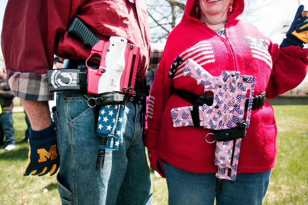 A couple holding patriotically decorated guns.