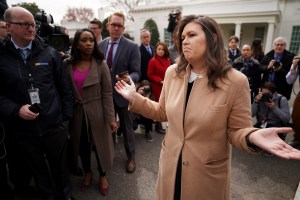 Sarah Huckabee Sanders shrugging while surrounded by reporters