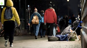 Passanten gehen an einer obdachlosen Person vorbei