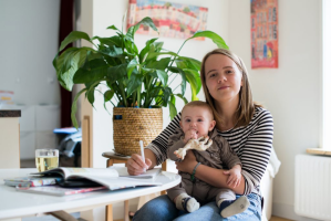 Vrouw met kind op schoot en pen in hand