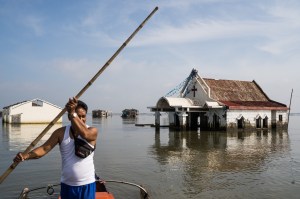 man in bootje bij zinkend dorp