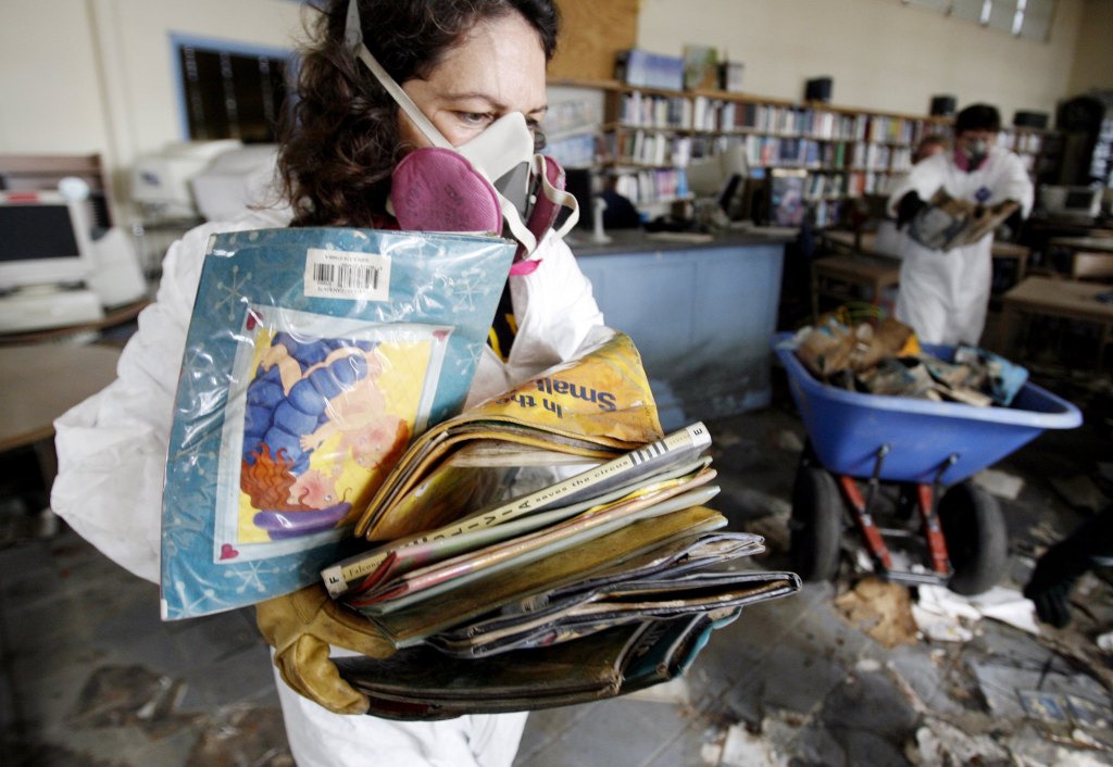 A member of the American Library Association carries destroyed books out while gutting the Nora Navra Public Library branch on June 26, 2006 in New Orleans, Louisiana a few months after Hurricane Katrina and Hurricane Rita.​