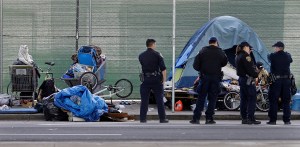 In this March 1, 2016 file photo, San Francisco police officers wait while homeless people collect their belongings in San Francisco. (AP Photo/Ben Margot, File)​​