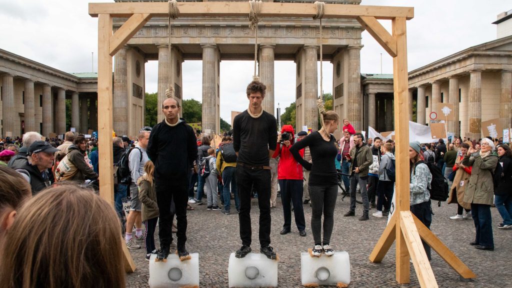 Drei Menschen an einem Galgen beim Klimastreik