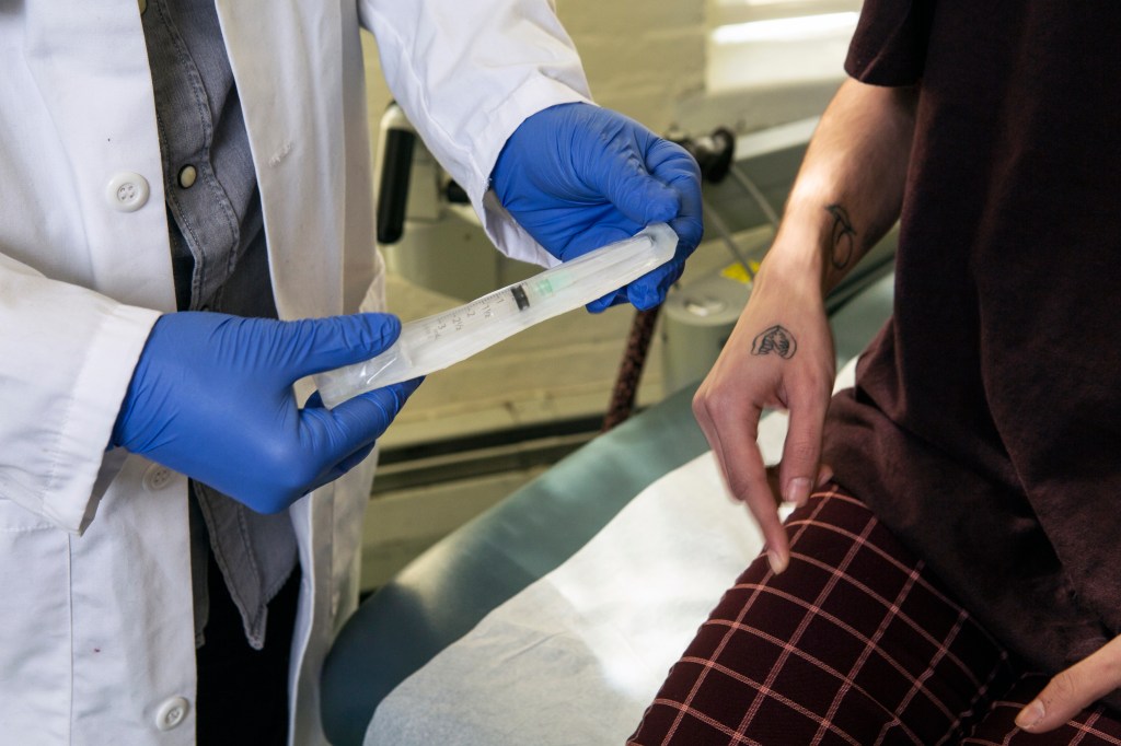 A doctor showing a patient a syringe used to inject testosterone