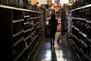 A shopper walks down a darkened aisle in a store.