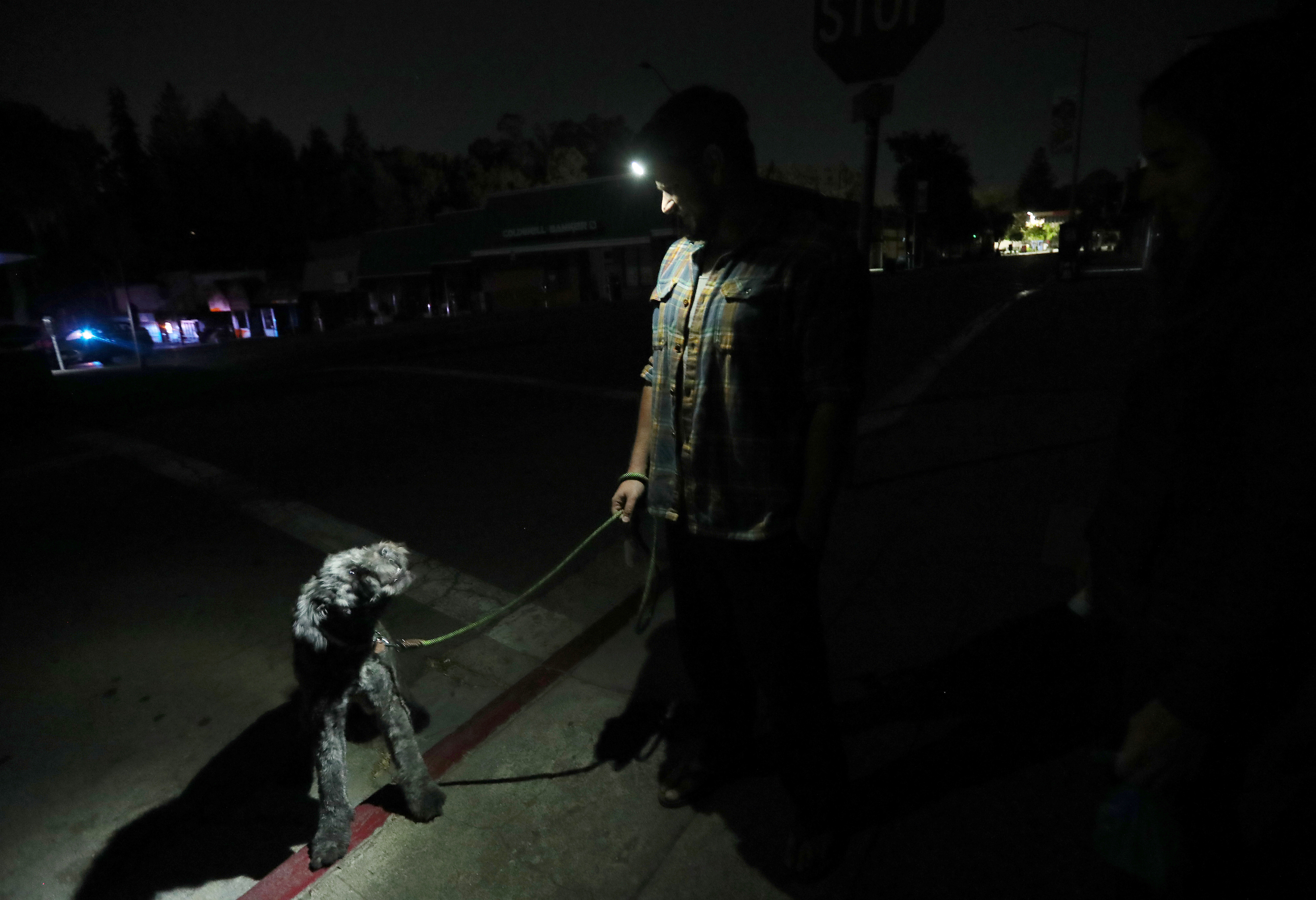 Tony, center, and Lauren Scherba walk their dog Gandalph minutes after the power went out in the Montclair District of Oakland, Calif., on Wednesday, Oct. 9, 2019. Power was supposed to go out at noon in Montclair, but the PG&E shutoff was delayed until approximately 10:37 p.m. (Photo by Jane Tyska/MediaNews Group/The Mercury News via Getty Images)