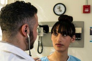 A transgender woman in a hospital gown having a conversation with a doctor, a transgender man