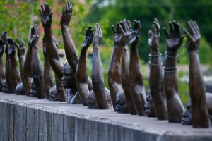 A statue of men with their arms raised at the lynching memorial.