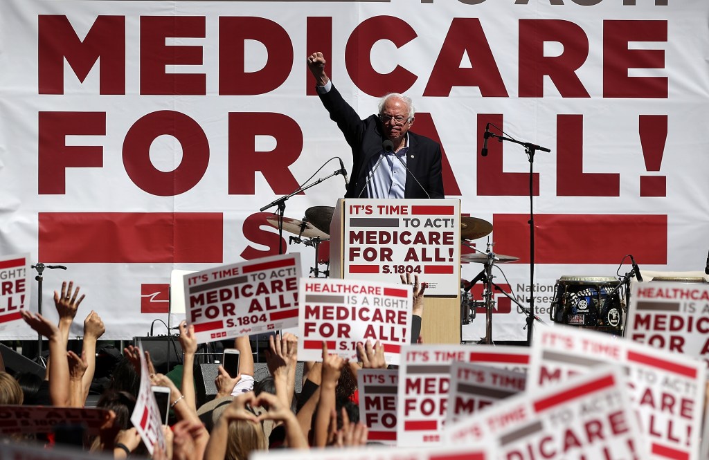 Bernie Sanders surrounded by Medicare for All signs