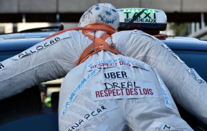 A dummy fixed to the hood of a taxi as taxi drivers block French roads in protest of Uber and other ride-hail companies. The dummy signs read "Uber - respect laws." Large protests in 2016 that led to today's French protests across seven cities against Ube