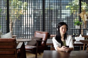 Seorang perempuan sedang mendengarkan musik di ruang kantor terbuka