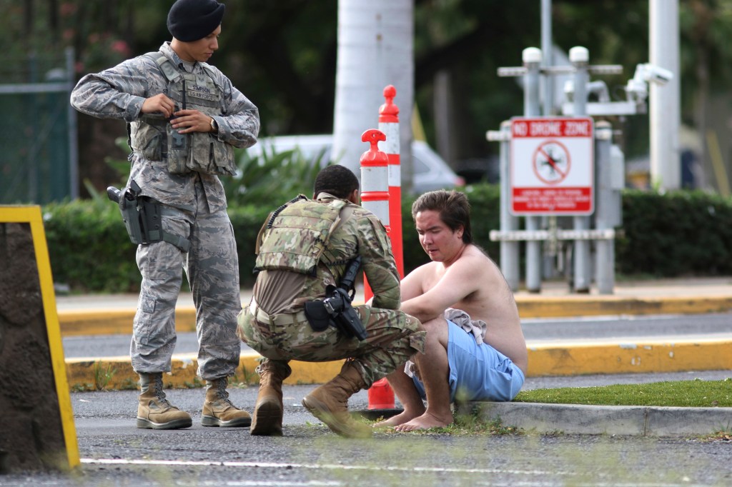 Security forces attend to an unidentified male outside the the main gate at Joint Base Pearl Harbor-Hickam, Wednesday, Dec. 4, 2019, in Hawaii, following a shooting.