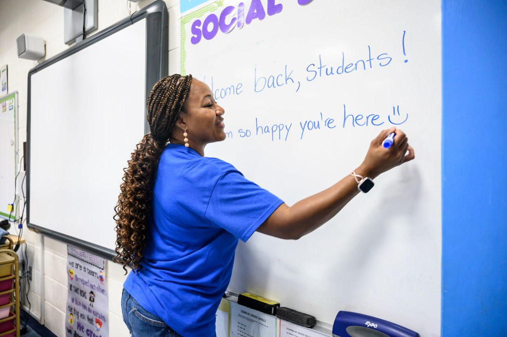 A teacher writes on a white board.