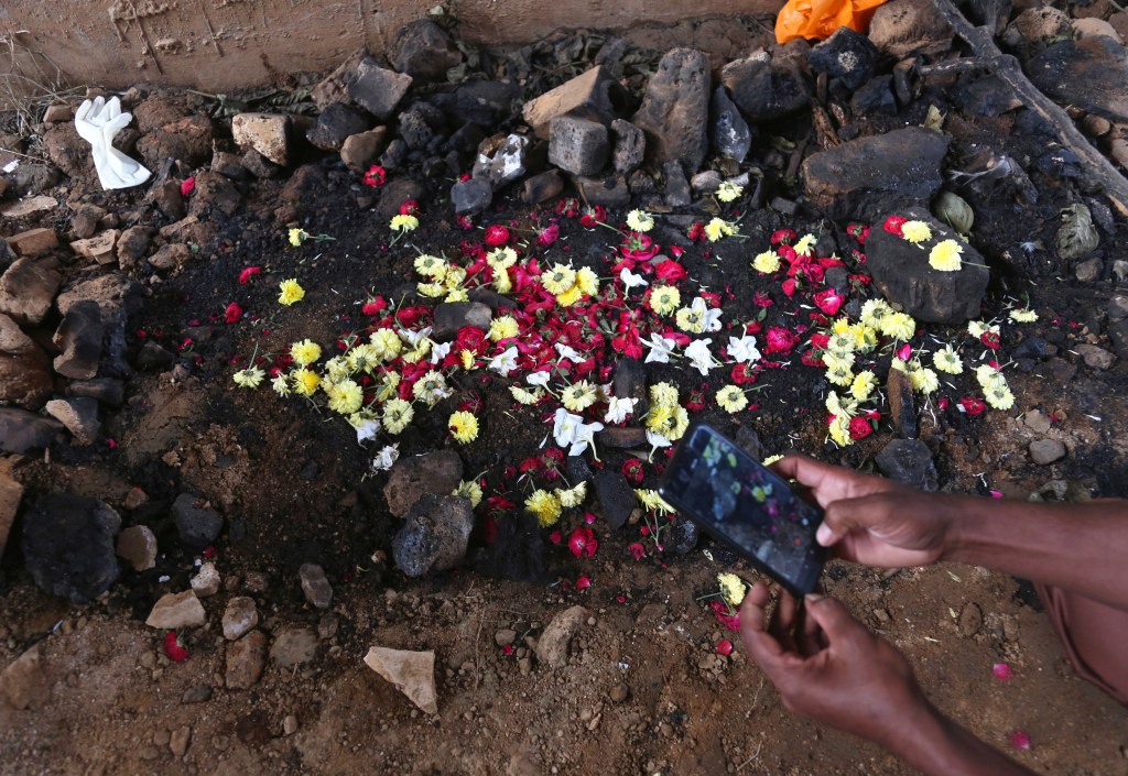 An Indian man takes photos of the site where the burned body of a 27-year-old woman was found last week by a passer-by, in Shadnagar some 50 kilometers or 31 miles from Hyderabad, India, Friday, Dec. 6, 2019.